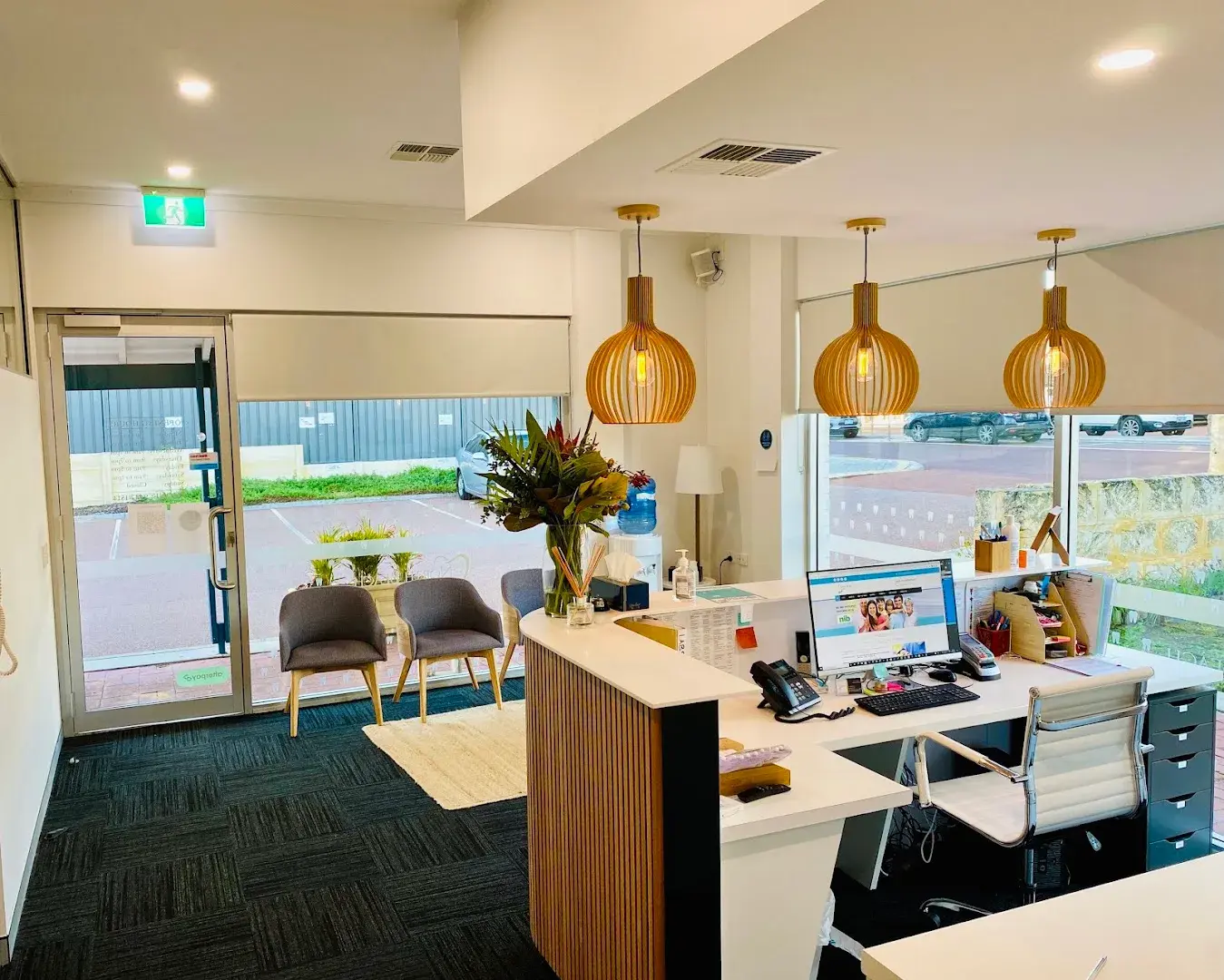 The reception desk and waiting area at North Beach Dental, with armchairs by the front door